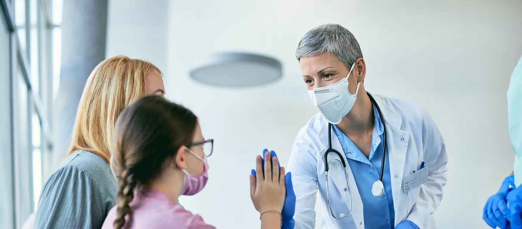 Doctor with a mask high-fives a young patient