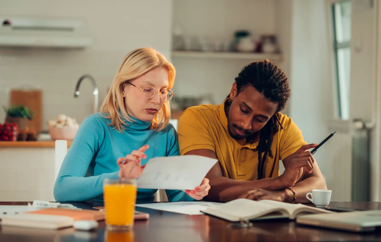 A man and woman examine papers at a table, engaged in discussion and analysis of the documents.