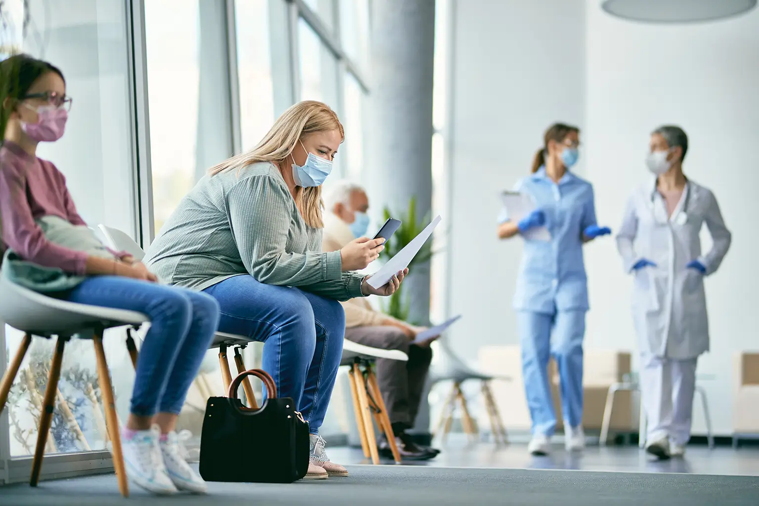 People sitting in a waiting area wearing masks of a medical complex