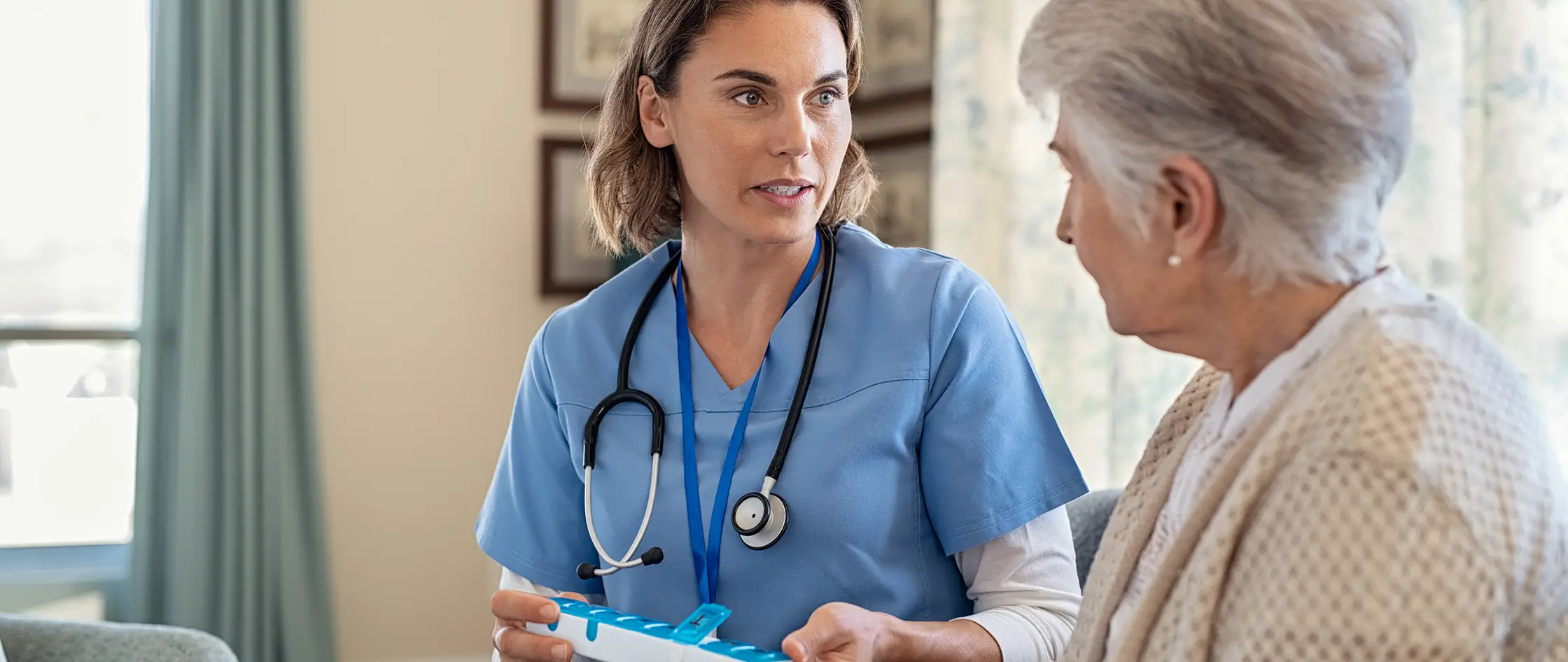 An elderly woman engages in conversation with a nurse, highlighting a moment of care and connection in a healthcare environment.